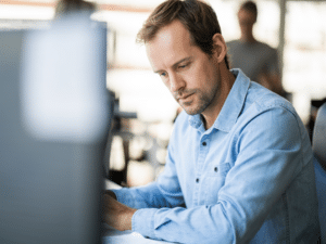 Professional man in blue shirt works at his desk