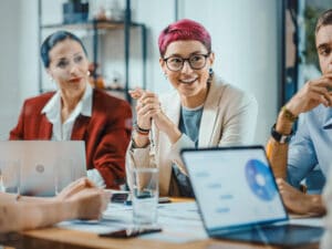 Office Meeting in Conference Room: Specialist with Short Pink Hair Talks about Firm Strategy with Diverse Team of Professional Businesspeople. Creative Start-up Team Discusses Big Project