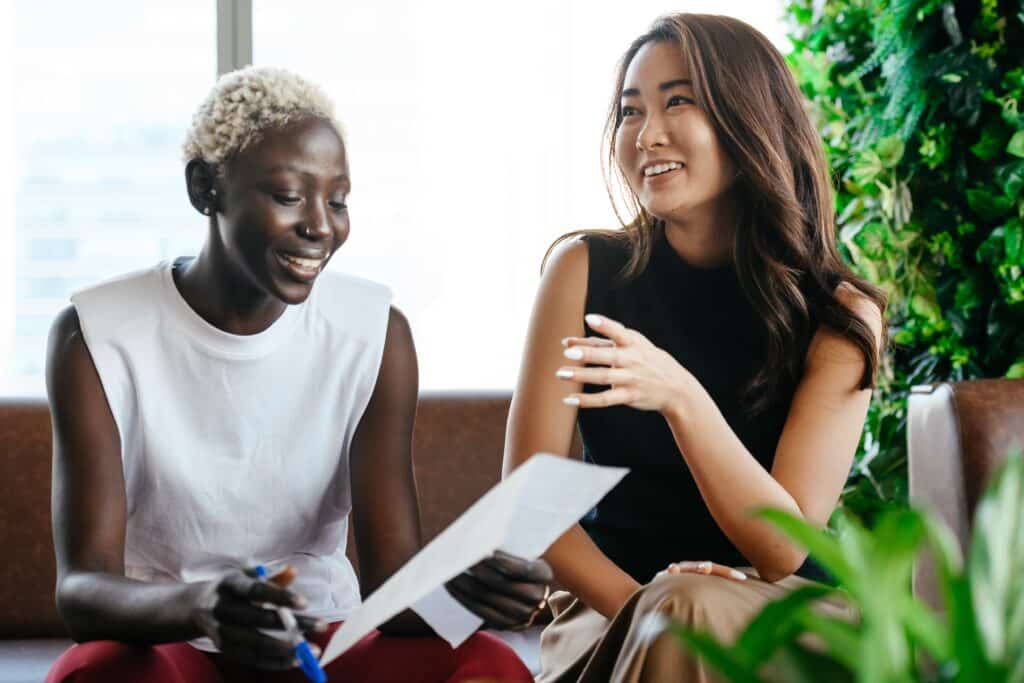 Two women sit down and smile at work