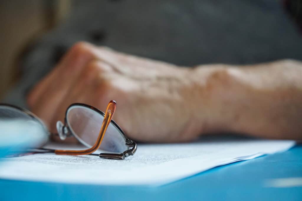 Hand and glasses on top of paperwork