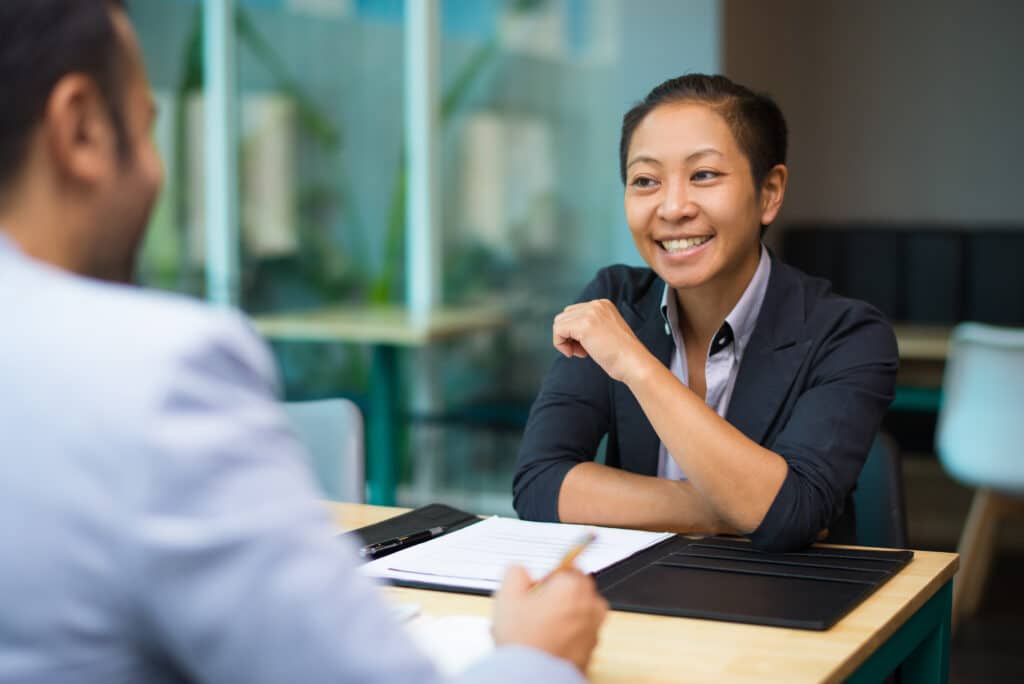 Happy excited businesswoman supporting idea of colleague while they discussing marketing strategy at meeting. Cheerful Asian woman analyzing data with colleague. Teamwork concept