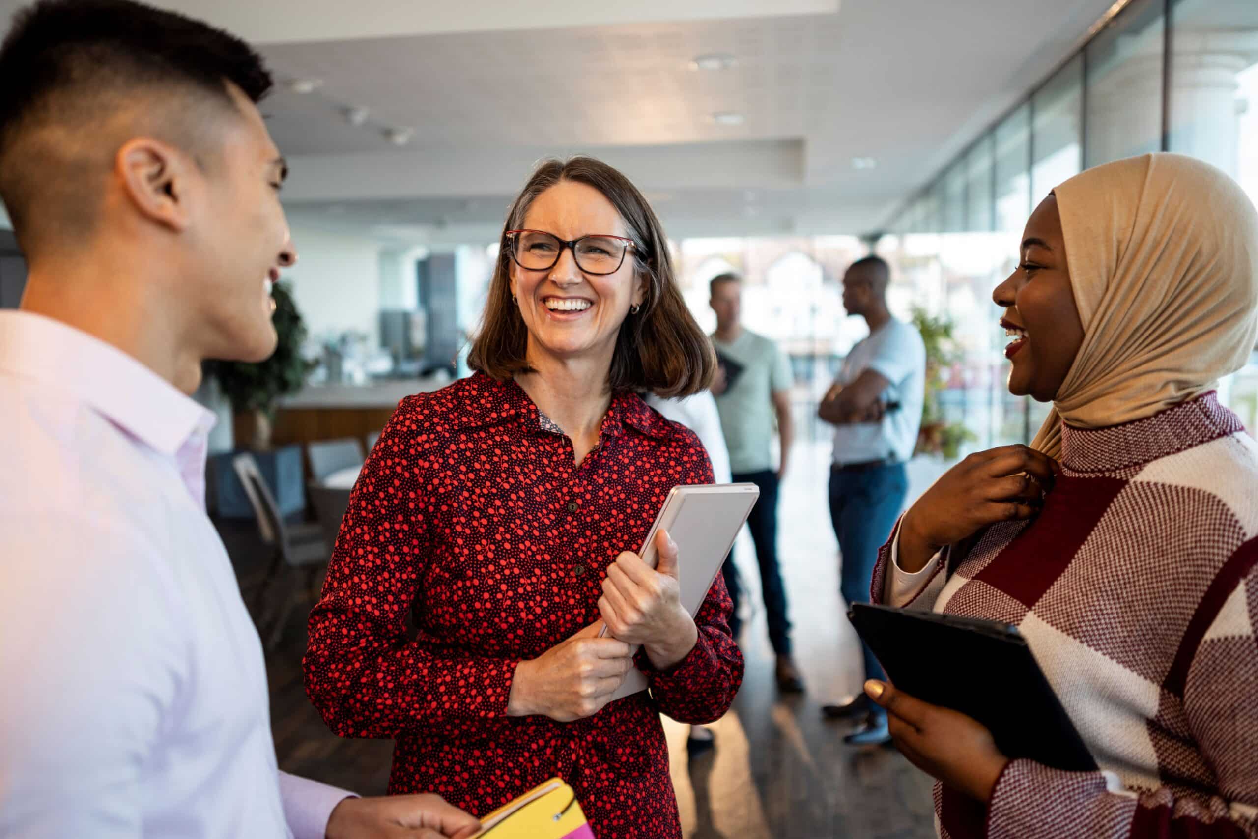 Three people talking and smiling in a modern office