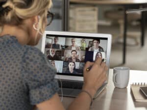 A woman on a video call with colleagues, watches her screen