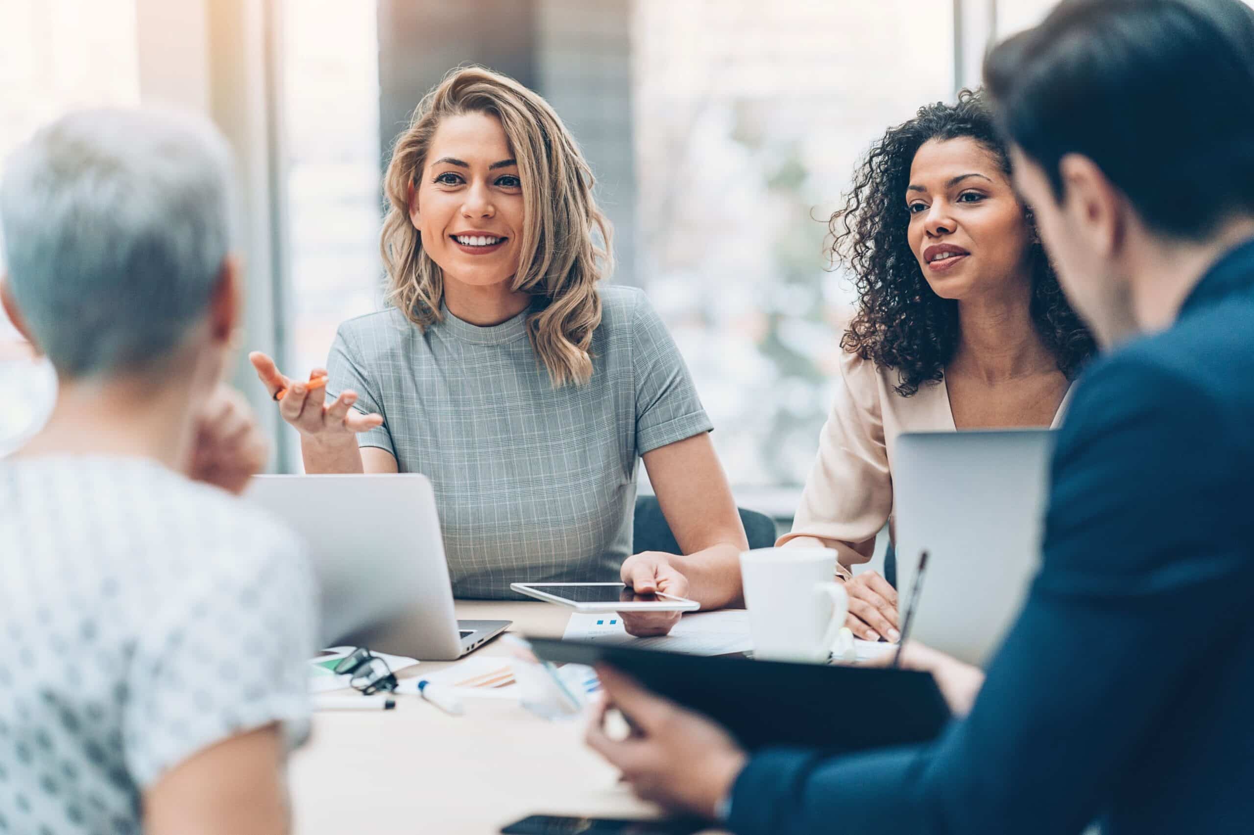 Four people smiling and talking in a corporate setting