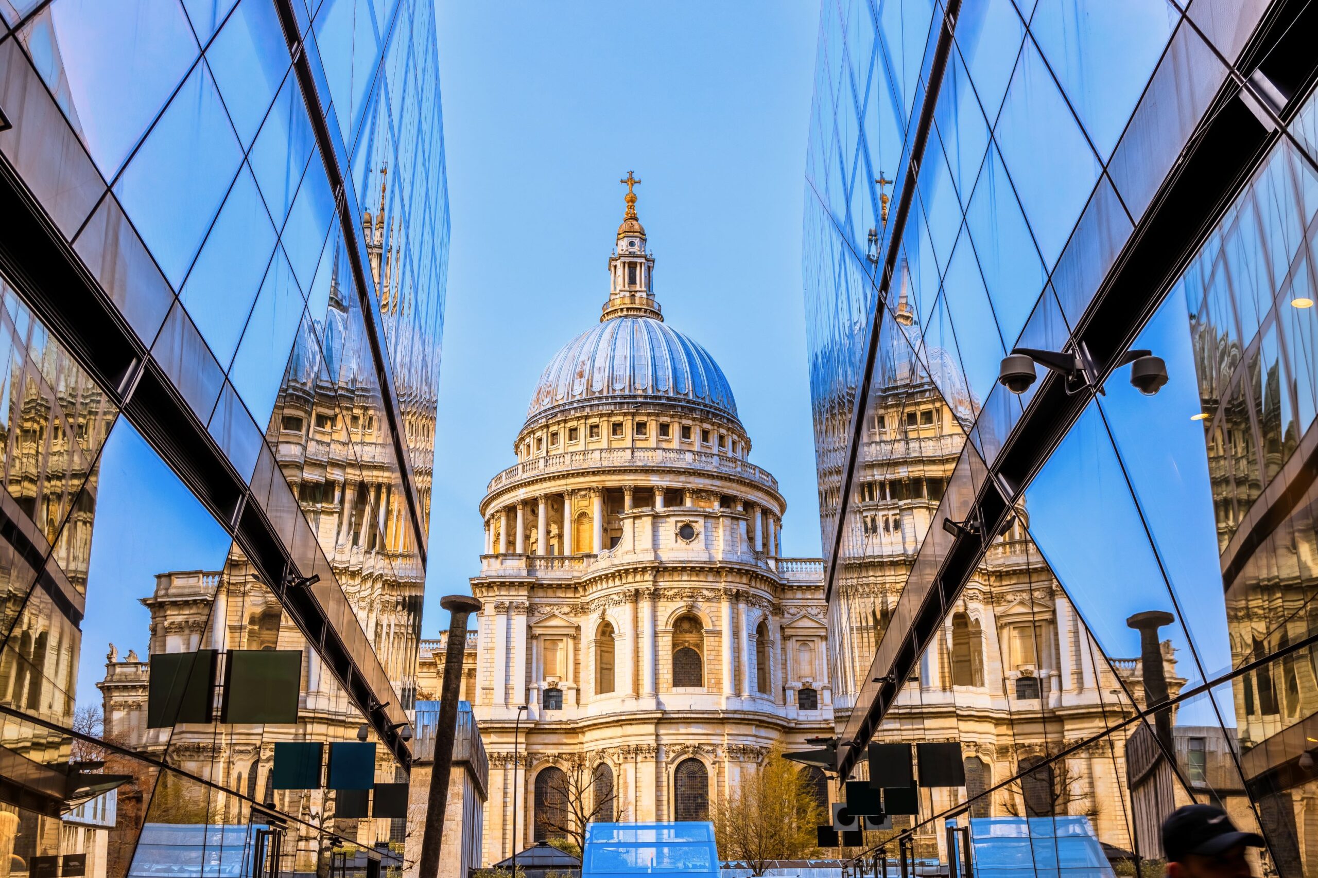 St Paul's cathedral through a glass alleyway against blue sky