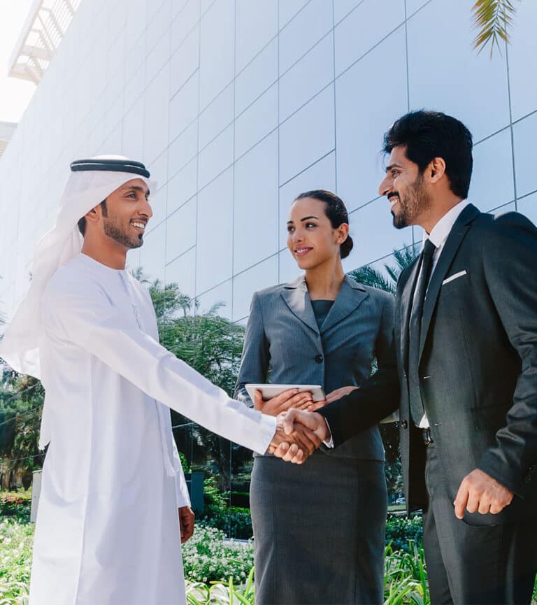 Colleagues in UAE shake hands during an outdoor business meeting