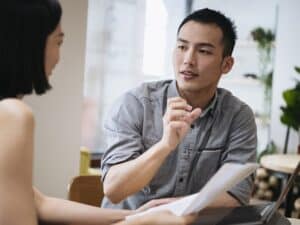 Young businessman gesturing to female coworker