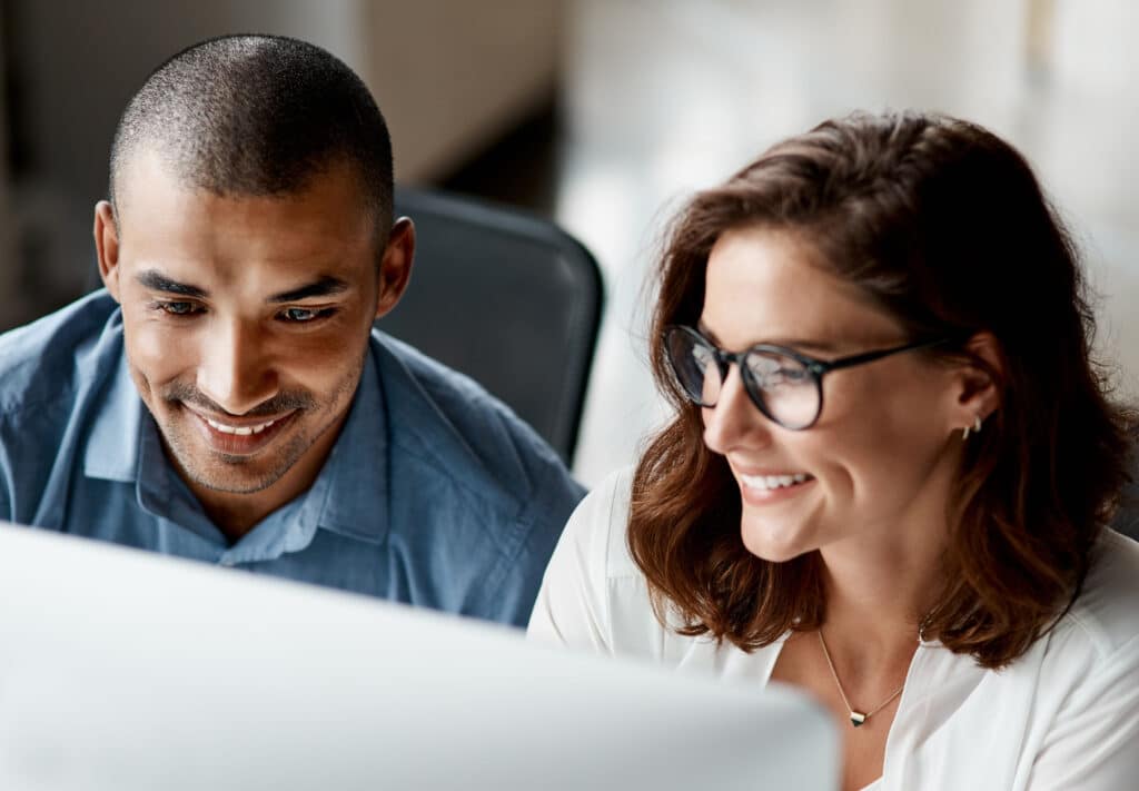 Shot of two young businesspeople sitting together in the office and using a computer