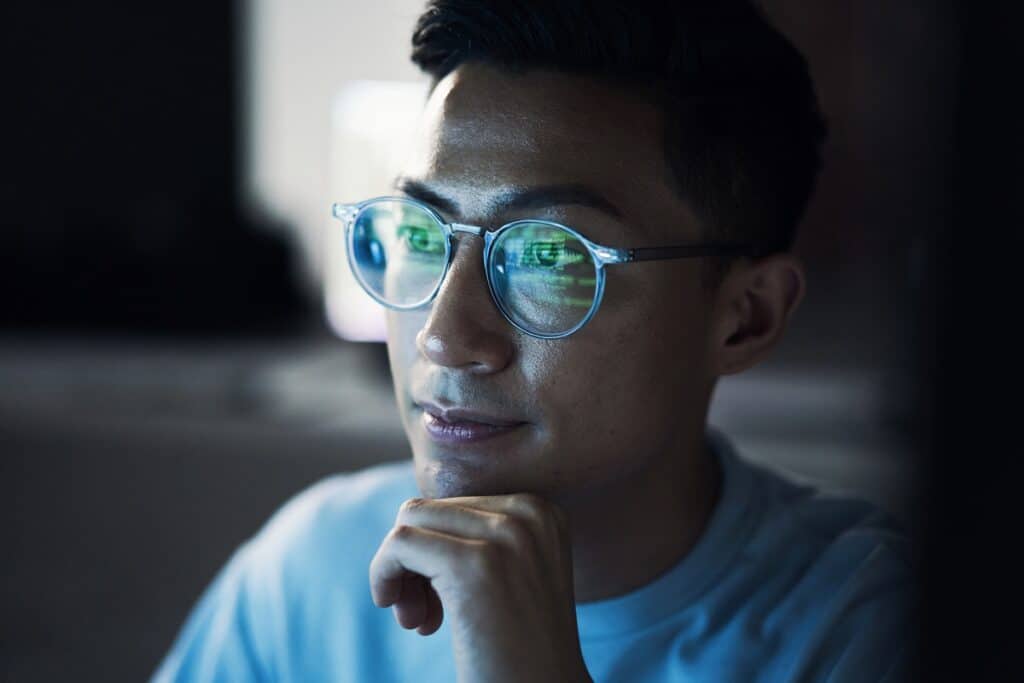 Asian man, developer and thinking in coding at night or programming software or application development. Male programmer or coder troubleshooting and working late on code in problem solving at office