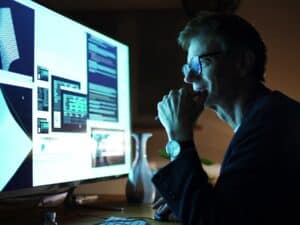 Close up stock photograph of a mature man working with a large computer screen. He’s working with 3D software examining complicated shapes.