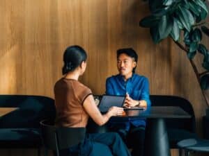 Two people sitting across from the table from one another