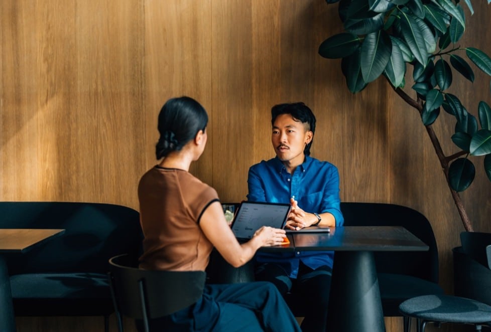 Two people sitting across from the table from one another