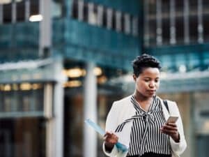Shot of a young businesswoman using a mobile phone on the go in the city