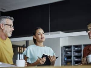 Businesswoman with diary and pen by colleagues