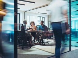 Group of business persons having a meeting in a closed glass conference room